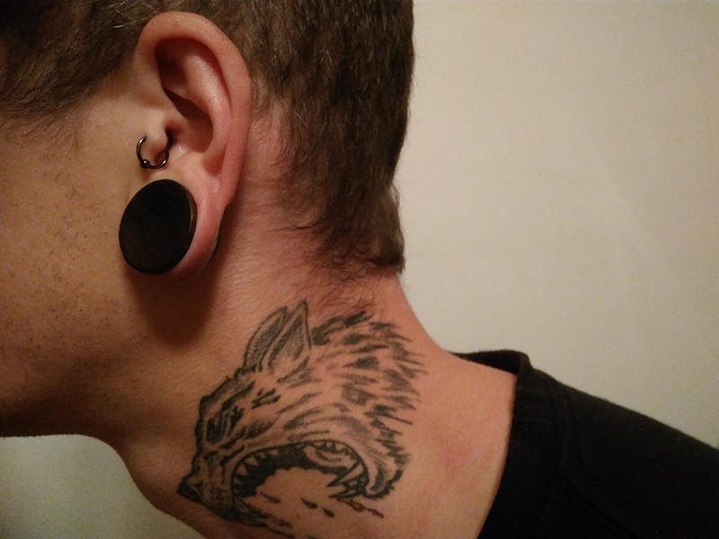 Muž s tetováním na krku a piercingy v uchu